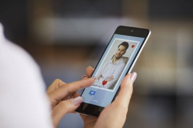 İnternette aşkı bulma kavramı. Kadın, çöpçatanlık sitesinde veya cep telefonu uygulamasında genç bir adamın fotoğrafını beğeniyor. Yakın plan, cep telefonu tutan elleri yakın çekim ve kırmızı kalp tuşuna basın.
