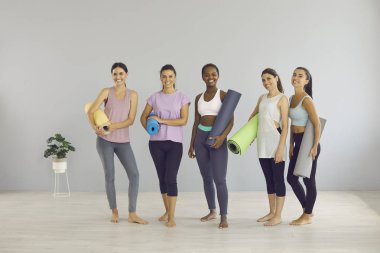 Gülümseyen milenyum jenerasyonunun portresi z çok ırklı kızlar spor salonunda grup egzersizi. Paspaslı, genç, etnik çeşitliliğe sahip kadınlar yoga yapıyor, spor yapıyor. Sağlıklı yaşam tarzı.