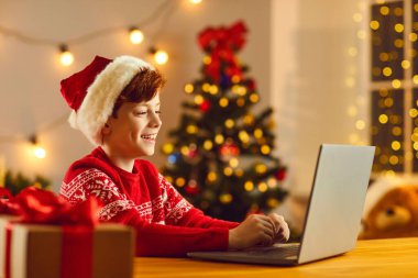 Noel arifesi evde. Noel Baba şapkalı küçük çocuk dizüstü bilgisayarın önünde oturuyor ve bir video görüşmesinde konuşuyor. Çocuk Noel tatilini internette herkesle konuşarak geçiriyor..