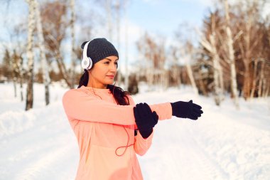 Kız sporcu kışın karda antrenmandan önce esneme hareketleri yapar..