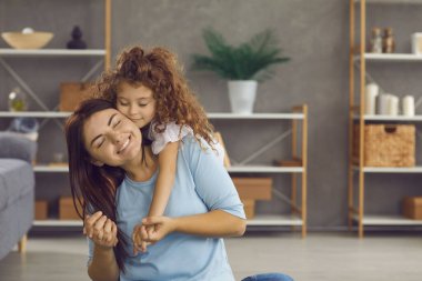 Sıkıca sarıl bana. Anne ve çocuk birbirlerini kucaklıyor ve mutlu hissediyorlar. Anne ve kızı evdeki modern oturma odasında yerde oturmuş gözleri kapalı gülümsüyor. Aile ve aşk kavramı