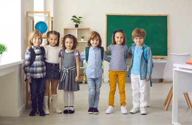 Okuldaki mutlu küçük çocukların toplu portresi ya da çocuk eğitim merkezi. Sınıfta durup gülümseyen ve kameraya bakan küçük bir grup ilkokul öğrencisi. Eğitim kavramı