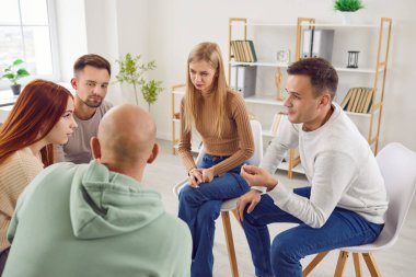 Grup psikoterapi seansı, gençler bir çemberin içinde oturup konuşuyorlar ve birbirlerine yardım ediyorlar. Bir psikologla terapi görüyorlar. Bir birliktelik duygusu ve karşılıklı destek sağlıyorlar..