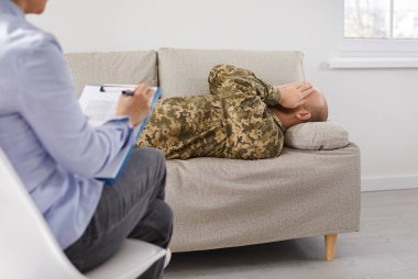 Travma sonrası stres bozukluğu olan asker psikologla görüşüyor. Profesyonel terapist sorular soruyor, hastaları dinliyor ve yazıyor. Askeri adam terapi sırasında kanepede uzanıyor ve yüzünü ellerine saklıyor.
