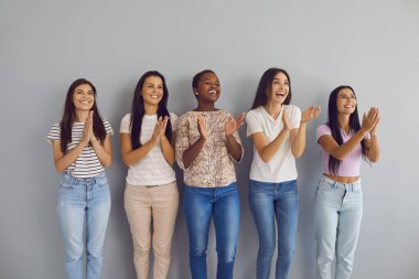 Çok ırklı kadın izleyiciler alkışlıyor. Gülümseyen genç bayanların alkışladığı bir grup. Duvarın kenarında el çırpan beş güzel bayanın stüdyo portresi.