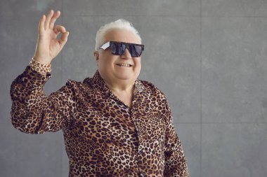 Leopar desenli gömlek, altın zincirli bilezik ve güneş gözlüğü takan neşeli, neşeli, şişman, şişman, şişman bir adam.