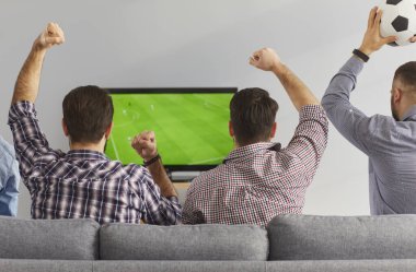 Erkekler televizyonda canlı yayında futbol maçı izliyor. Heyecanlı erkek arkadaşlar rahat koltukta oturup ilginç futbol şampiyonası izliyorlar, tezahürat yapıyorlar, bağırıyorlar ve en sevdikleri takımı destekliyorlar.