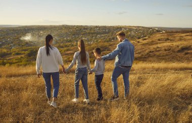 Oğlu ve kızı olan dört kişilik genç bir aile dışarıda güzel doğanın tadını çıkarıyorlar. Mutlu bir anne-baba, iki çocuklu bir baba birlikte tarlada yürüyorlar. Aile eğlence konsepti.