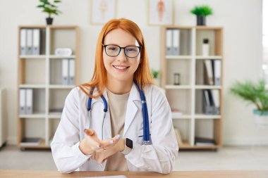Hastanede online video görüşmesi yapan pozitif bir hemşire ya da doktorun portresi. İnternet kamerasıyla hastalarla ya da iş arkadaşlarıyla konuşuyor, internette tıbbi muayeneleri tartışıyor..