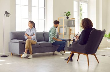 Genç ve evli bir çift, terapi seansı sırasında aile terapisti ofisinde karşı koltukta oturup birbirlerini görmezden geliyorlar. Tartışma, boşanma ve akıl sağlığı kavramı.