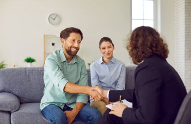 Mutlu, genç ve evli bir çift terapi seansından sonra danışmanlık koltuğunda oturup erkek aile psikologu ile tokalaşıyor. Aile terapisi ve akıl sağlığı konsepti.