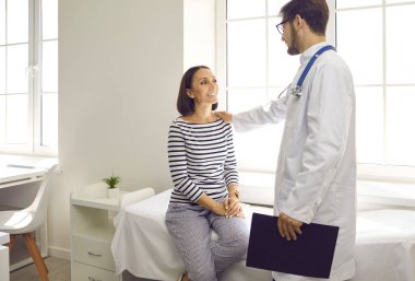 Klinikteki dost canlısı doktor hastayla konuşuyor. Hastanedeki muayene koltuğunda oturan mutlu orta yaşlı kadın doktorların iyi analiz sonuçları hakkında söylediklerini dinliyor. Güven, bakım, yardım, destek kavramı