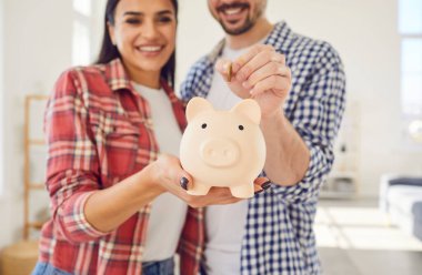 Evde bir çiftin portresini çekmek, domuzcuk kumbarasına neşeyle para koymak. Aile birikimlerini sevgi ve birliktelikle oluştururken ortak bir finansal birlik anı..