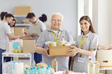 Mutlu ve gülümseyen gönüllülerin portresi, son sınıf erkek ve genç kadın, bir bağış kutusunu tutan bir yardım kuruluşundan. İnsani yardım ve yardım, toplumsal yardım kavramı.