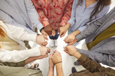 Bir grup insan el ele tutuşarak bir çember oluşturuyorlar. Birlik ve ortaklıkları, işbirliği ve iş arkadaşı desteğini vurgulayarak takım içindeki güçlü bağı gösteriyor.