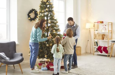 Aile, Noel ya da yeni yıl hazırlıkları için evde birlikte bir ağaç süsler. Kutlamalar onları yakınlaştırıyor, ortak sevinç anları ve bayram gelenekleri sayesinde..
