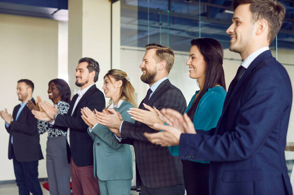 Деловые люди аплодируют, дружелюбные разнообразные сотрудники поздравляют с достижениями в бизнесе, отличными результатами работы, продвижением по службе, аплодисментами, пребыванием в современном офисе, продвижением, признанием, уважением