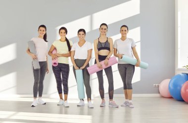 Spor salonunda spor yaparken kameraya gülümseyen mutlu kadın sporcuların toplu portresi. Takım pozitif enerji ve fitness eğitimine adanmışlık, spor ve spor için coşku gösterisi.