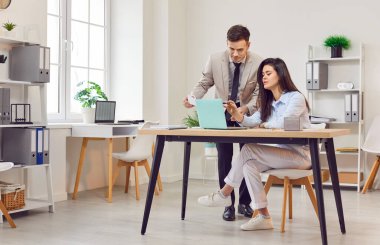 İş görüşmesi ya da brifing sırasında ofiste dizüstü bilgisayarla çalışan iş arkadaşları. Profesyonel bir ortamda iş birliği, takım çalışması ve iş arkadaşları arasında aktif tartışma.