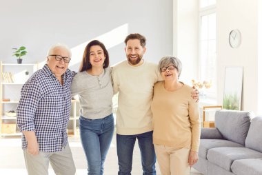 Mutlu, yaşlı bir çiftin aile portresi. Yetişkin bir erkek ve kız. Evde birlikte duruyorlar. Yaşlı ebeveynler çocuklara sevgi gösterirler. Aile bağı, sevgi ve birliktelik..