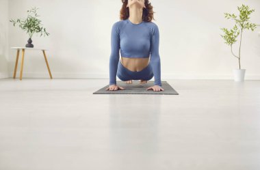 Genç kadın yoga yapıyor, yukarı doğru köpek egzersizi yapıyor, Urdhva mukha shvanasana pozu veriyor, spor giyiniyor, beyaz yoga stüdyosu, temiz zemin kaplaması.