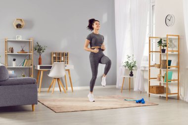 Kadın antrenman seansının bir parçası olarak yerinde koşuyor. Düzenli koşma, koşu ve spor yaparak spor yaparak aktif ve sağlıklı kalmaya odaklanıyor..