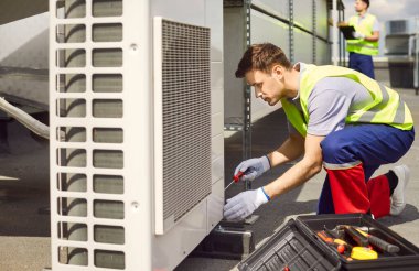 Elektrikçi çatıdaki havalandırma ya da havalandırma sisteminde bakım ya da onarım çalışması yapıyor. Uzmanlıkları havalandırma ve hava kontrol sisteminin verimli çalışmasını sağlıyor..