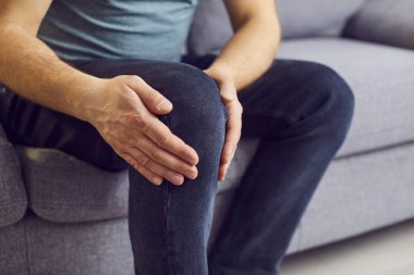 Yaklaş, masaj yap, dizine elle dokun, acı hisset, bacağın ağrıyor, kanepede otur, kendini kötü hisset, sağlık problemi kavramı, osteoartrit, sağlık problemi 