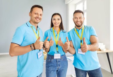 Bir grup mutlu, gülümseyen gönüllü toplum bağış merkezinde çalışıyor kameraya neşeli bakıyor ve işaret veriyor. Gönüllü olma kavramı.