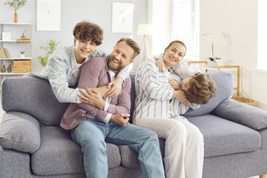 Mutlu çocukların portresi, aileleriyle eğlenen, evdeki kanepede oturan çocukların portresi. Çocuklarla vakit geçiren genç bir çiftin portresi. Aile eğlence konsepti.