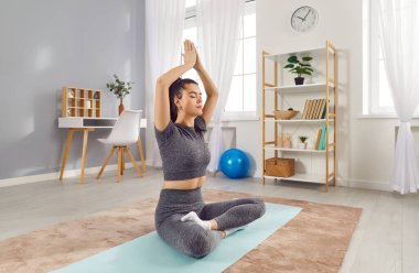 İnce, güzel bir kız evde yoga pozuyla yerde oturuyor. Spor giyim sektöründe genç bir kadın meditasyon yapıyor. Yoga egzersizleri, meditasyon, tefekkür ve konsantrasyon, stresten kurtulma.