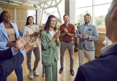 Bir grup mutlu iş adamı toplantı odasında sırada hoparlörleri alkışlıyor. Başarılı iş arkadaşları ve şirket çalışanları iş eğitiminde veya konferansta bir meslektaşlarını alkışlıyorlar.