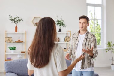 A man and a woman quarrel at home in a living room, a close-up. The wife proves her rightness to her husband. Concept family quarrel. Poor family communication, bossy woman, emotions clipart