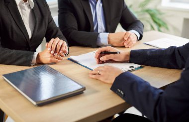 Masada oturan çiftin erkek emlakçıyla ya da mali danışmanıyla görüştüğü yakın çekim. Sigortacı danışman kadın ve erkek bir iş sözleşmesi imzalayacaklar..