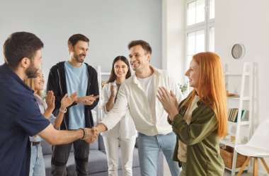 Bir grup mutlu genç kız ve erkek evde toplanıp daireler çizerek el sıkışıyor ve içeride birbirlerini selamlıyorlar. Arkadaşlık, parti, insanlar ve ev eğlencesi konsepti.