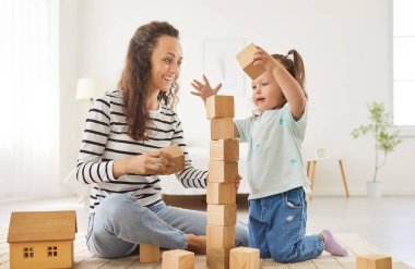 Mutlu, neşeli, gülümseyen anne ve kız bebek bakıcısı, bebek bakıcısı, blok inşa oyunu, dost canlısı, sevgi dolu bir aile, birlikte iyi vakit geçirin, küçük tatlı bir kızla güzel bir hafta sonu geçirin.