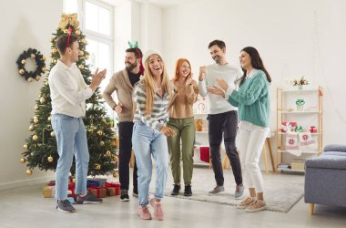 Mutlu gülümseyen genç insanlar arkadaşlar erkekler ve kadınlar parti veriyor, süslü Noel ağacıyla şenlikli salonda dans ediyorlar birlikte yeni yılı kutluyorlar. Kış tatili kavramı.