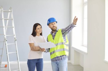 Uzman bir tamirci müşteriyle konuşan bir mimar. Daire planı belgelerini değerlendiriyor. İşbirlikçi inşaat projesi planlıyor, boya seçiyor, tasarım yapıyor. 