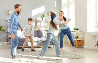 Evde neşeli, neşeli bir aile, iki çocuklu anne ve baba oturma odasında kör adam oyunu oynuyorlar, haftasonu anının tadını çıkarıyorlar, ebeveynler ve çocuklar birlikte eğleniyorlar, ev içi aktiviteler, eğlence.
