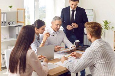 Bir grup ofis çalışanı masaya oturur ve yakın plan bir belgeye bakar. İş adamları bir şirket sorununu birlikte tartışıyor. Geliştirme bölümü takım çalışması konsepti, yatırımcı seçimi