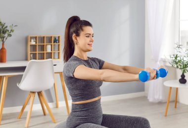 Spor kıyafetleri, dambıllar, sabah egzersizi yapan kız, evde kadın antrenörü, spor salonu, kanepe sağlıklı aktif yaşam tarzı, vücut eğitimi.