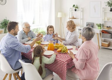 Mutlu, mutlu bir ailenin portresi. Genç ebeveynler, büyük ebeveynler ve iki çocuk. Birlikte akşam yemeğinin keyfini çıkarıyorlar..
