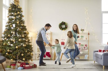 Aile bayramı komik dansı, anne ve baba ve iki küçük çocuk Noel arifesinde evde birlikte eğleniyorlar geleneksel yeni yıl tatillerini kutluyorlar, festival ağacı yakınında geleneksel aktivitelerin tadını çıkarıyorlar.
