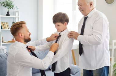 Family of three generation men tying tie, senior grandfather, father, son, child grandson at home wearing same formal wear, to show family resemblance between, celebrating fathers day holiday event clipart