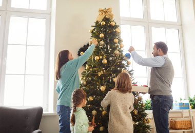 Çocuklu aile Noel ya da yeni yıla hazırlanıyor, evde birlikte bir şenlik ağacı süslüyorlar. Aile bağları, tatil beklentileri ve samimi bir aile ortamında neşeli bir ruh..