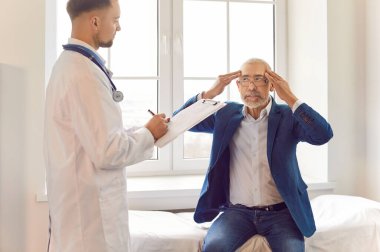 Hasta, doktor muayenehanesinde kanepede oturup baş ağrısı çeken ya da migreni olan yaşlı bir adam. Klinikteki tıbbi muayene sırasında yaşlı bir erkek hasta. Sağlık ve Tıp Konsepti.