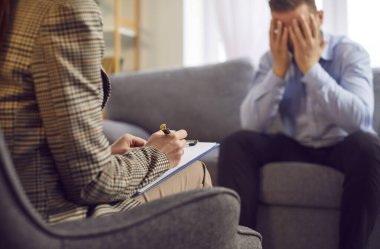 Bir psikologla terapi seansı sırasında ağlayan üzgün bir adam. Bu duygusal an, erkeklerin üzüntüsünü ve zihinsel sağlık desteği ve rehberlik istemenin önemini vurguluyor..