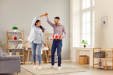 Evde mutlu bir çift, oturma odasında eğleniyorlar, birlikte dans ediyorlar, yeni daireyi ya da yıldönümünü kutluyorlar, yakışıklı genç koca güzel eş elini tutuyor, taşınıyor eğleniyor, flört ediyor, hediye kutusu veriyor.