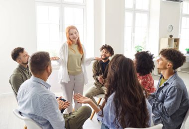 Gündelik giysiler içinde iş projesini tartışan genç iş adamları daireler çizerek oturuyorlar ve genç bir bayan meslektaşı ofiste konuşurken dinliyorlar. Takım çalışması konsepti.