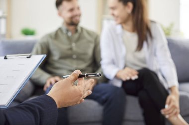 Genç bir aile çiftiyle terapi seansı sırasında psikoloğun ellerine yakın durun. Konsültasyonda destek, yardım ve ilişki sorunları üzerinden konuşma üzerinde duruluyor.